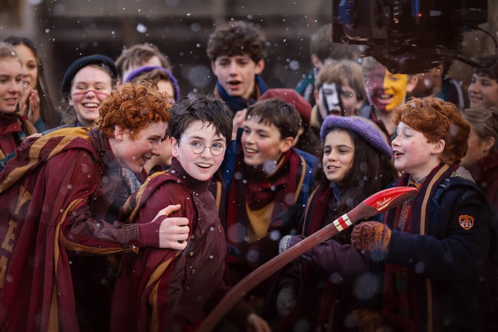 Dominic McLaughlin as Harry Potter in Quidditch uniform surrounded by Gryffindor teammates in the Harry Potter series